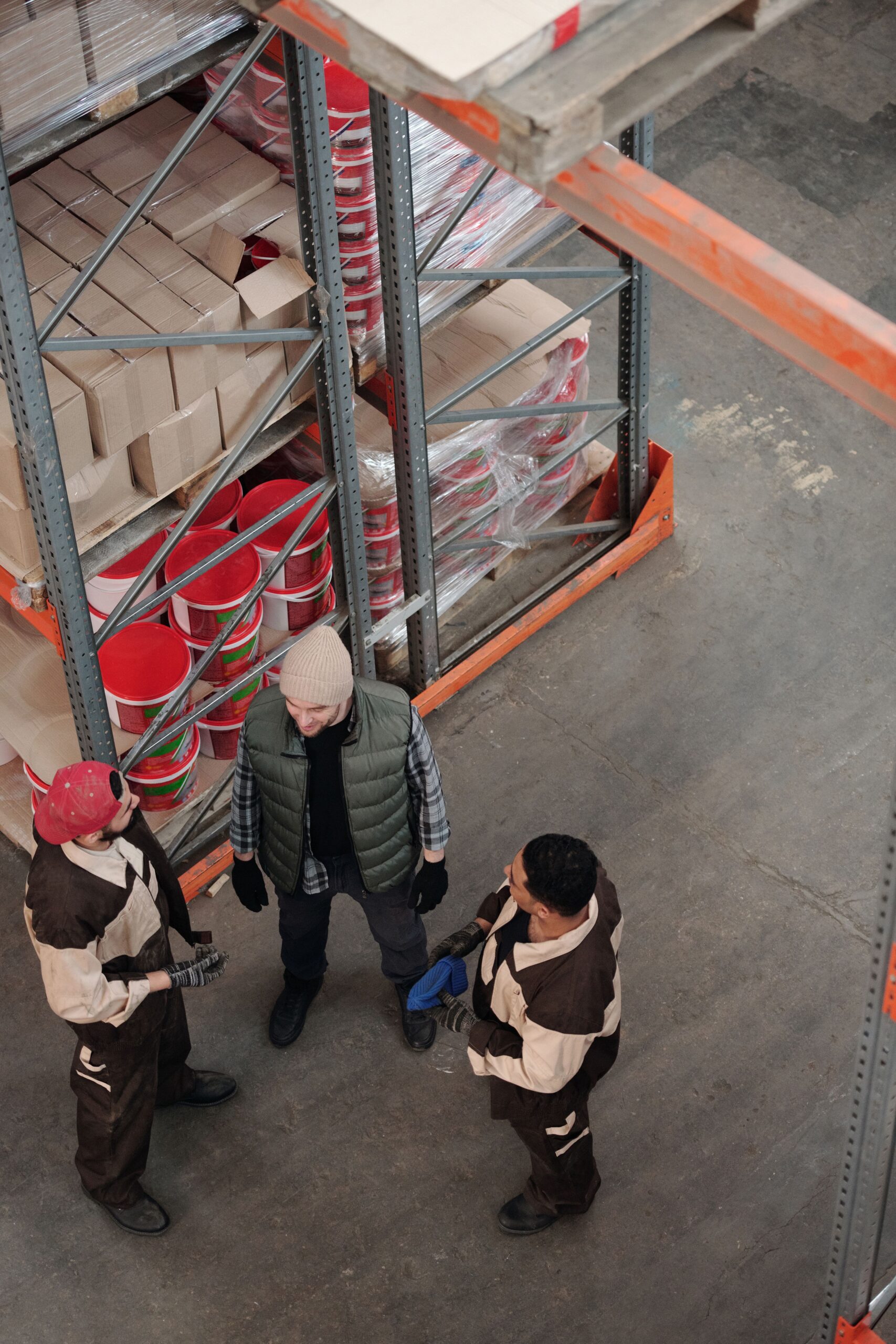 High-angle view of a team discussing logistics in an industrial warehouse setting.